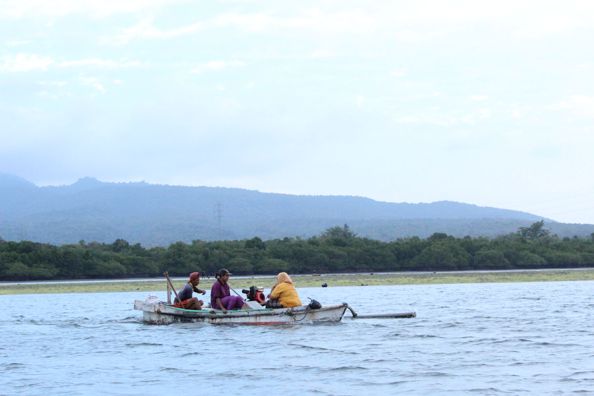 Local fishermen paddling a traditional jukung across Gilimanuk Bay, Bali