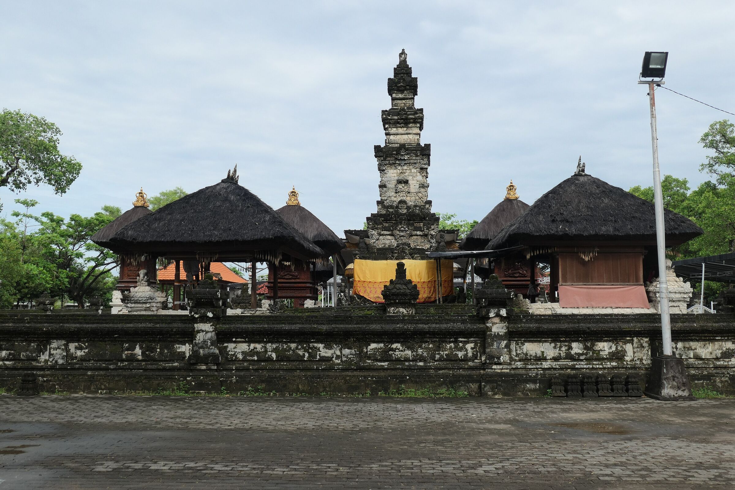 The main temple courtyard of Pura Sakenan on Serangan Island, with thatched shrines and a stone prasada