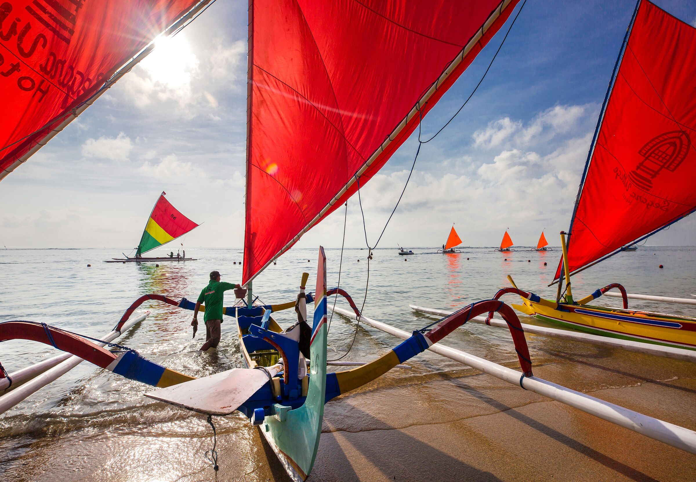 Jukung boats with red sails setting out from Sanur beach